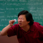 Ator Ken Jeong faz esforço para ler algo em um pedacinho de papel