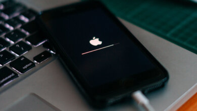 Foto de um iPhone ligado ao cabo com a tela preta e o logo da maçã