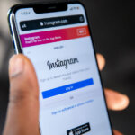 Mão segurando um iPhone com o Instagram aberto