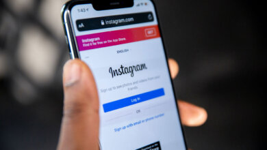 Mão segurando um iPhone com o Instagram aberto