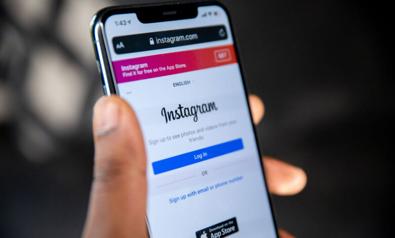 Mão segurando um iPhone com o Instagram aberto